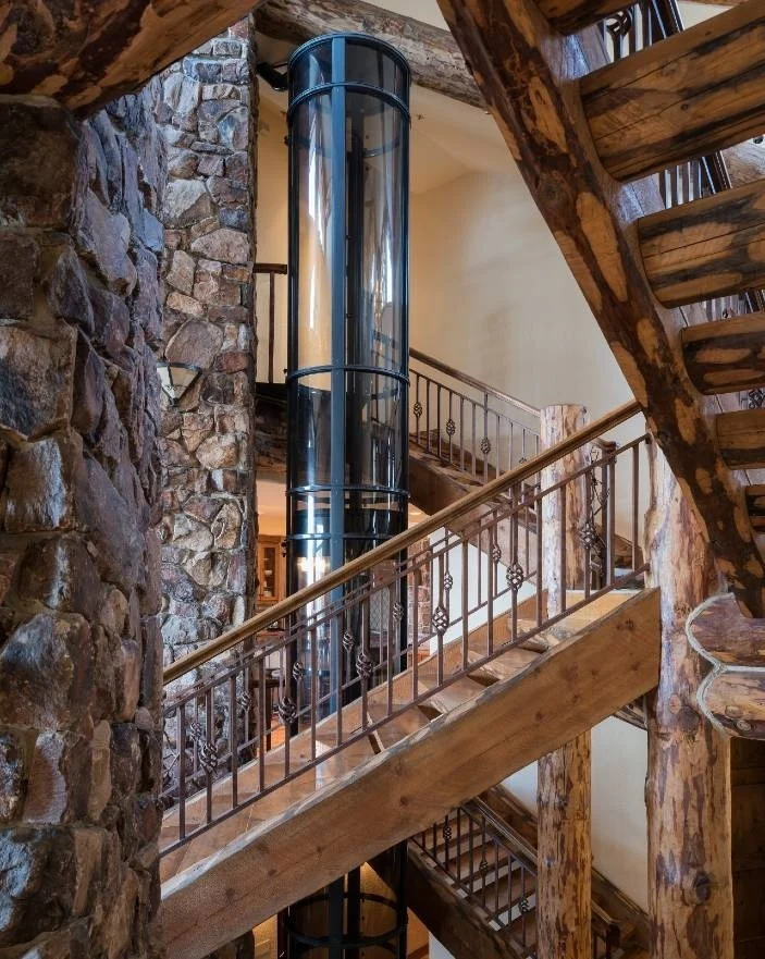 PVE Vacuum Elevator in Log Home Stairwell PVE vacuum elevator with black trim installed beside a rustic log staircase for Canada homes